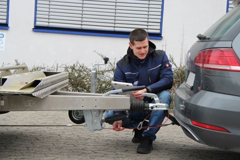 Prüfingenieur prüft vor der TÜV SÜD Prüfstelle Gaimersheim die Zugvorrichtung eines Pkw-Anhängers